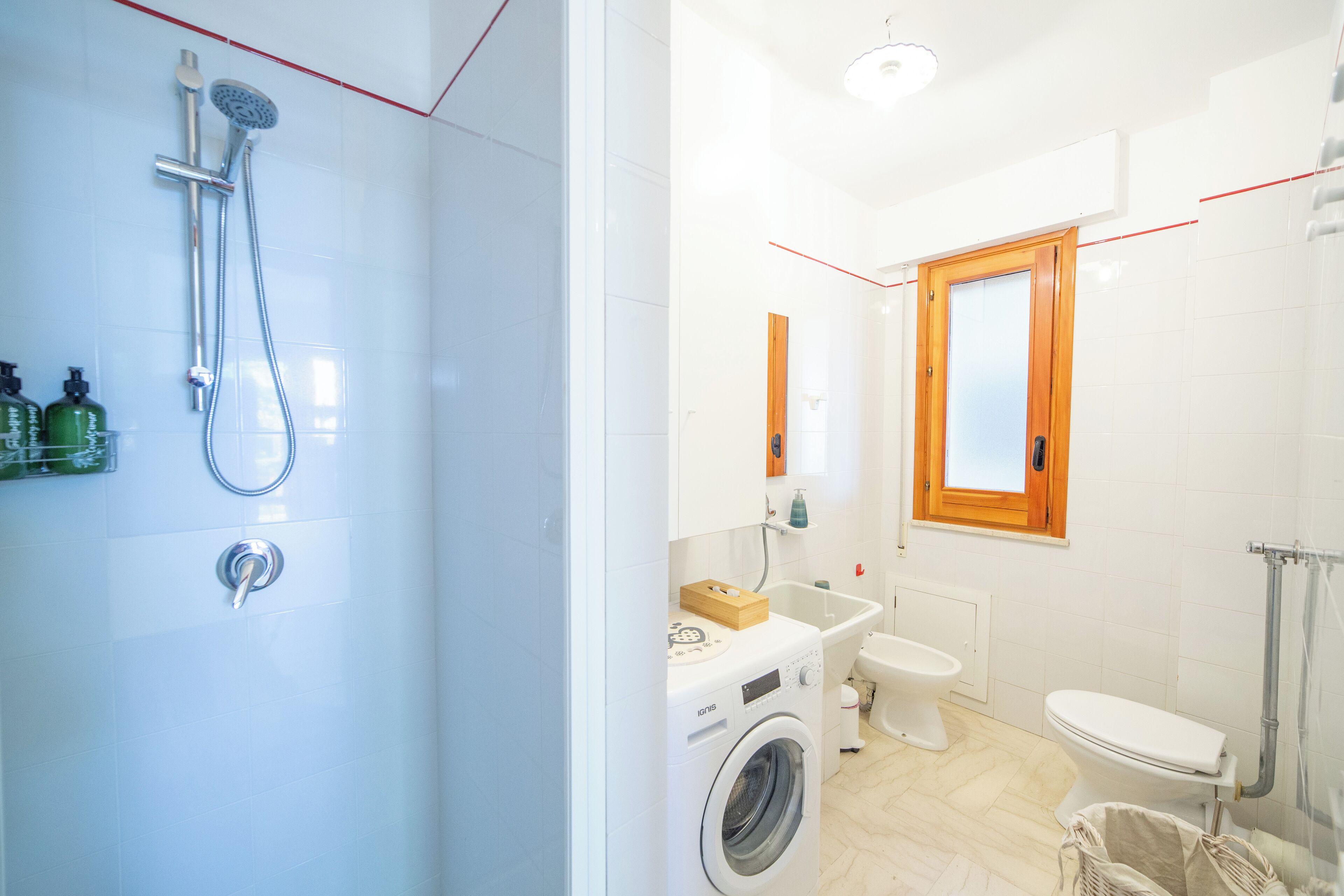 Une salle de bain moderne équipée d’une douche, d’un lave-linge, de toilettes et d’un lavabo.