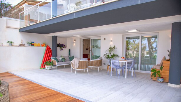A modern outdoor patio with a wooden floor, white furniture, and potted plants. - Marina Beach Apartments (Alcamo)
