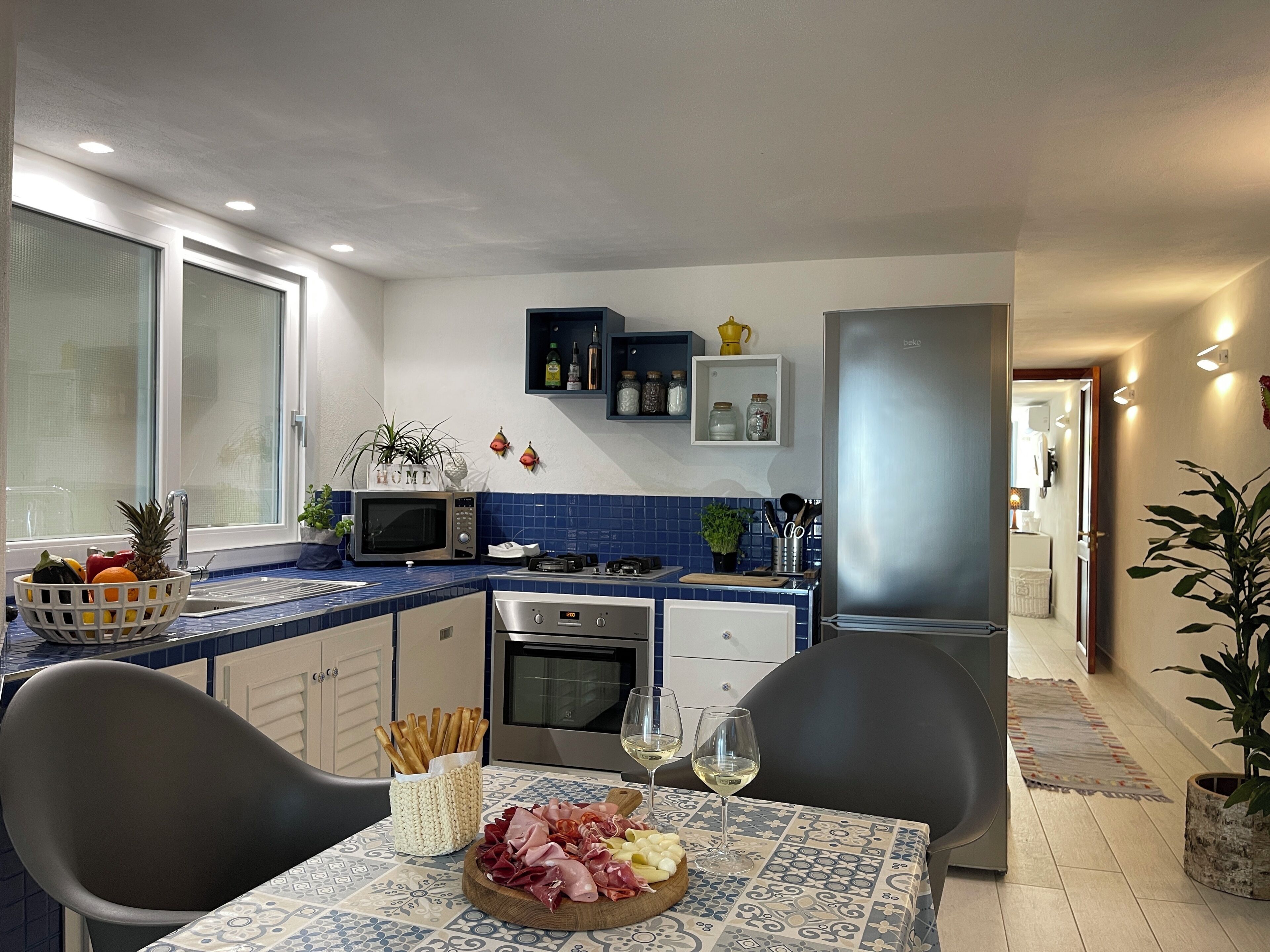 Una cocina moderna con comedor, que incluye microondas, horno y una mesa con una tabla de embutidos y copas de vino.