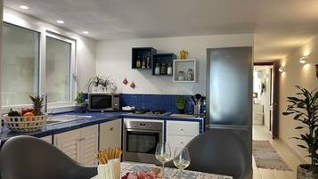 Una cocina moderna con comedor, que incluye microondas, horno y una mesa con una tabla de embutidos y copas de vino.