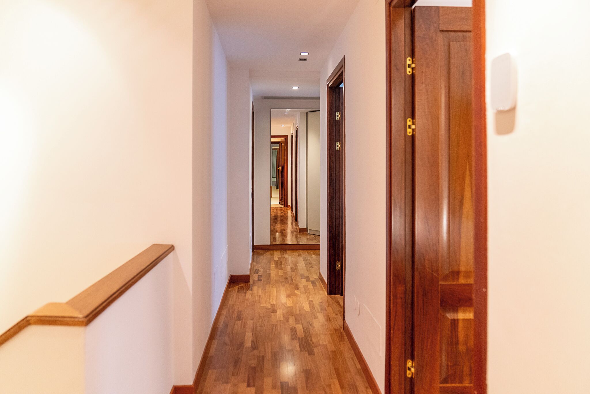 A hallway with wooden flooring and a wooden door on the right.