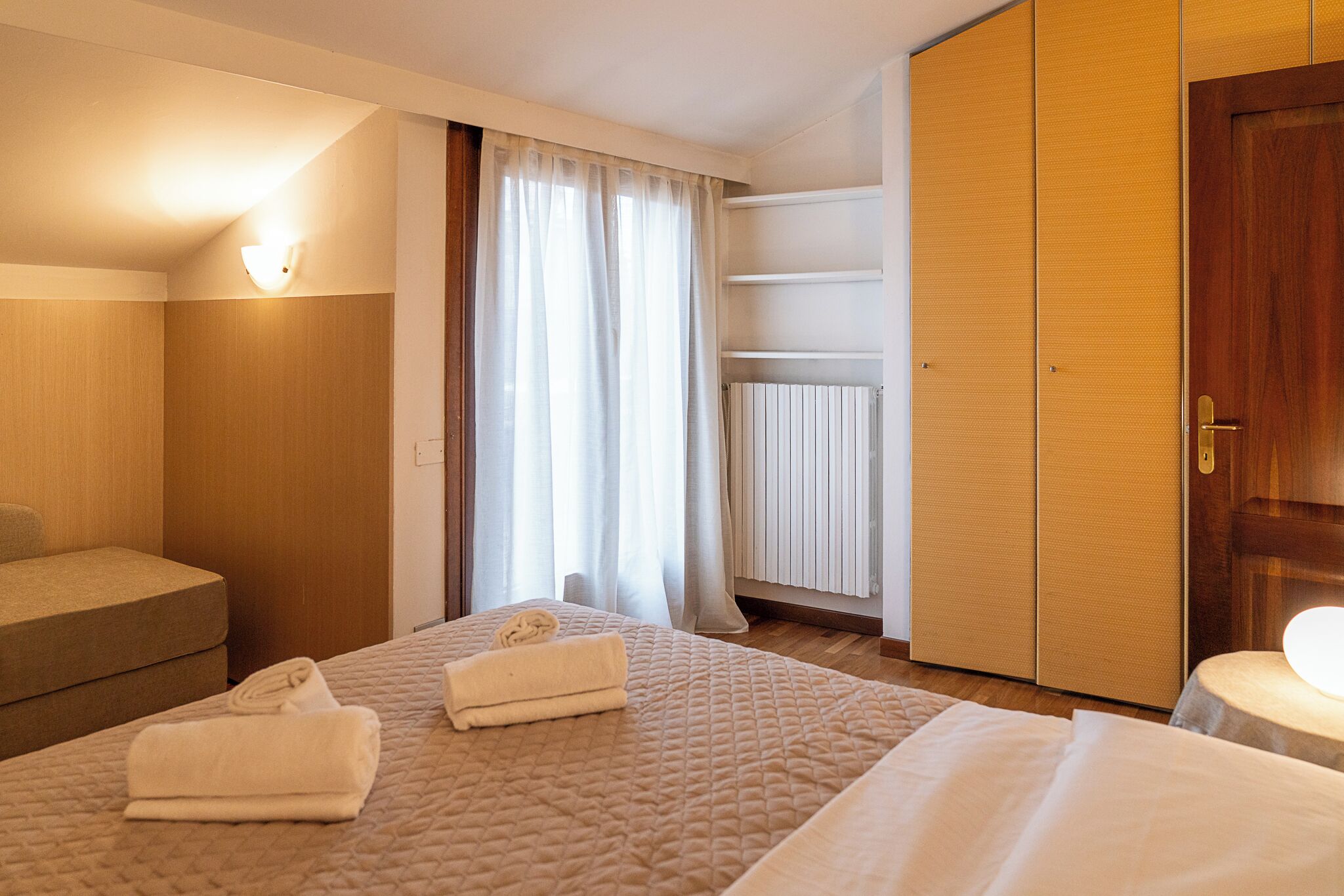 Une chambre d’hôtel comprenant un lit, un canapé, une table de chevet, une lampe et une armoire.