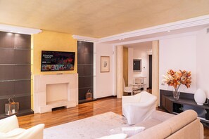 Uma sala de estar moderna com lareira, uma TV de tela plana montada acima e um sofá.