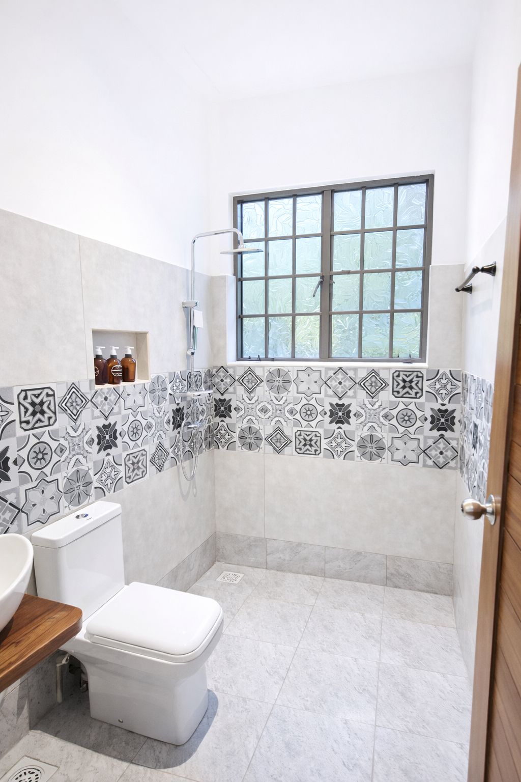A bathroom with a toilet, a sink, a shower, and a window.