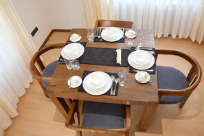 Een eettafel gedekt voor vier personen, met stoelen, een placemat en een tafelkleed.