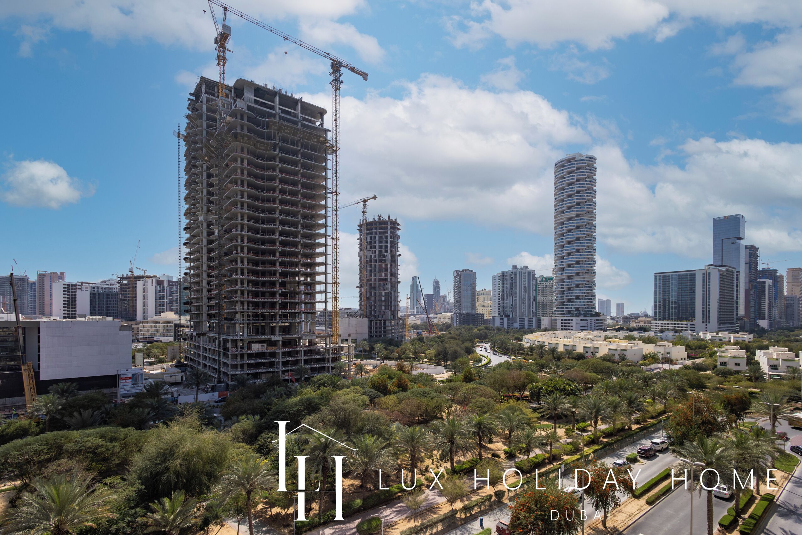Un immeuble de grande hauteur en construction, offrant une vue sur le paysage urbain et les palmiers.