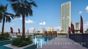 A luxury holiday home with a swimming pool, palm trees, and a view of tall buildings. - LUX The Hadley JVC Suite (Dubai)