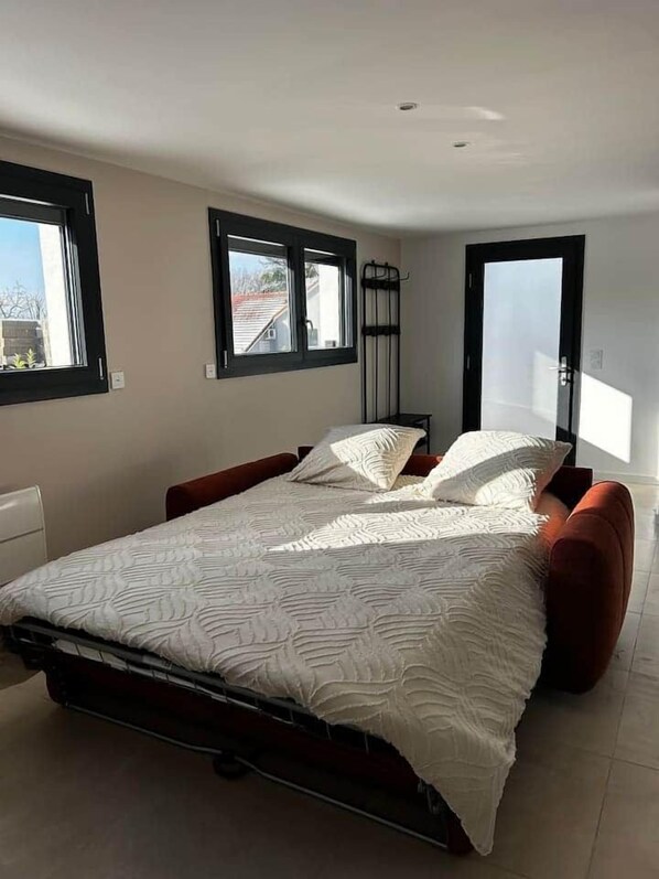 A bedroom with a bed, two windows, a door, and a radiator.