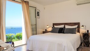 A bedroom with a large bed, a view of the sea, and a sliding glass door. - Vacation home Quenza by Interhome (Porto Vecchio)