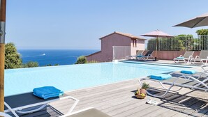 A pool area with lounge chairs and umbrellas, overlooking a clear blue sea. - Vacation home Quenza by Interhome (Porto Vecchio)
