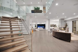 Un espacio habitable amplio y moderno con una escalera de madera, una chimenea y una barandilla de cristal.