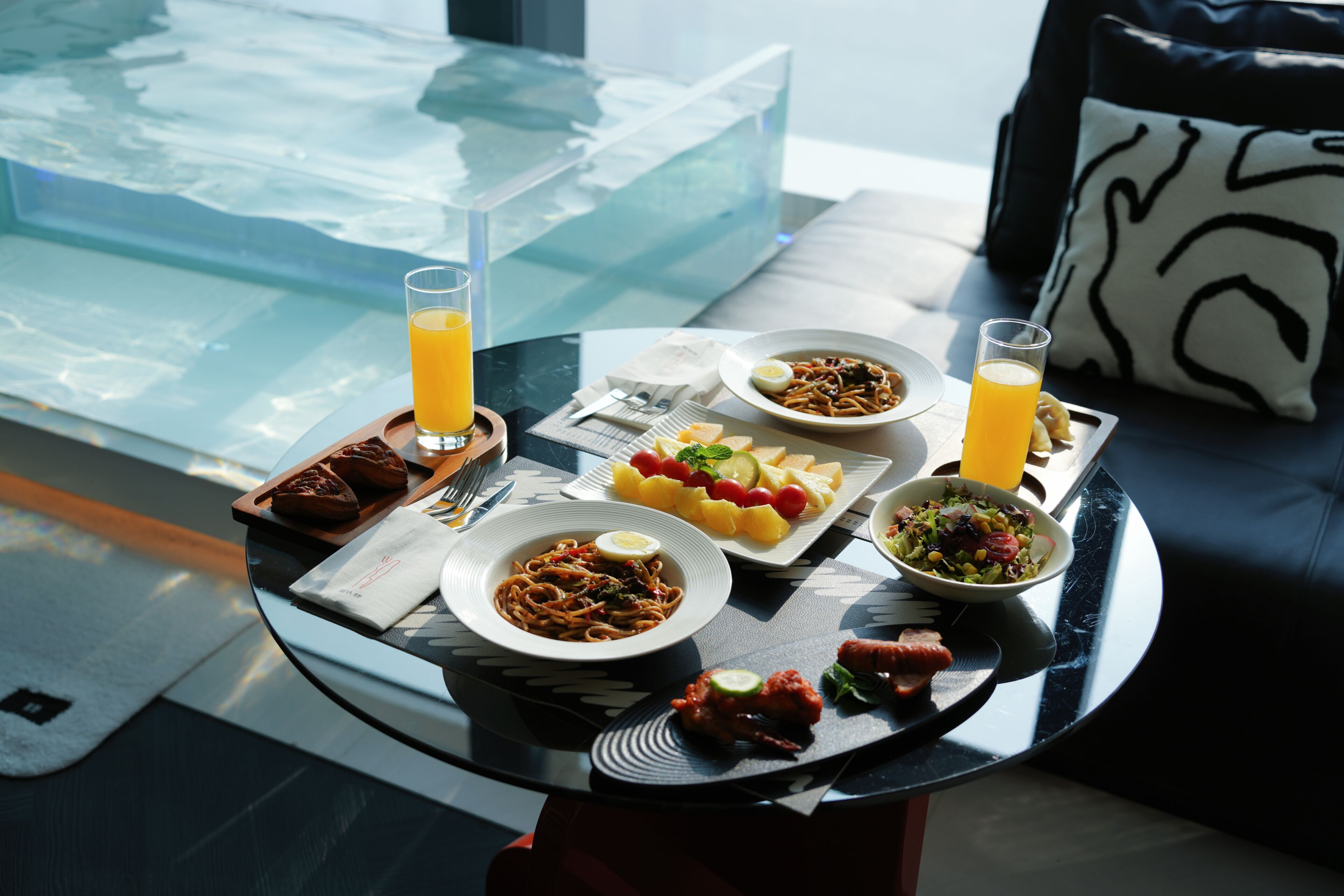 A dining table with plates of food, glasses of orange juice, and a glass of water.