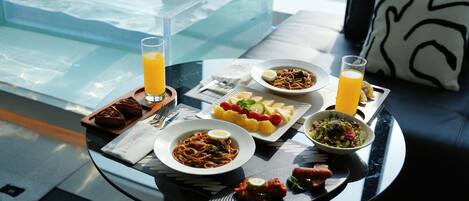 A dining table with plates of food, glasses of orange juice, and a glass of water.
