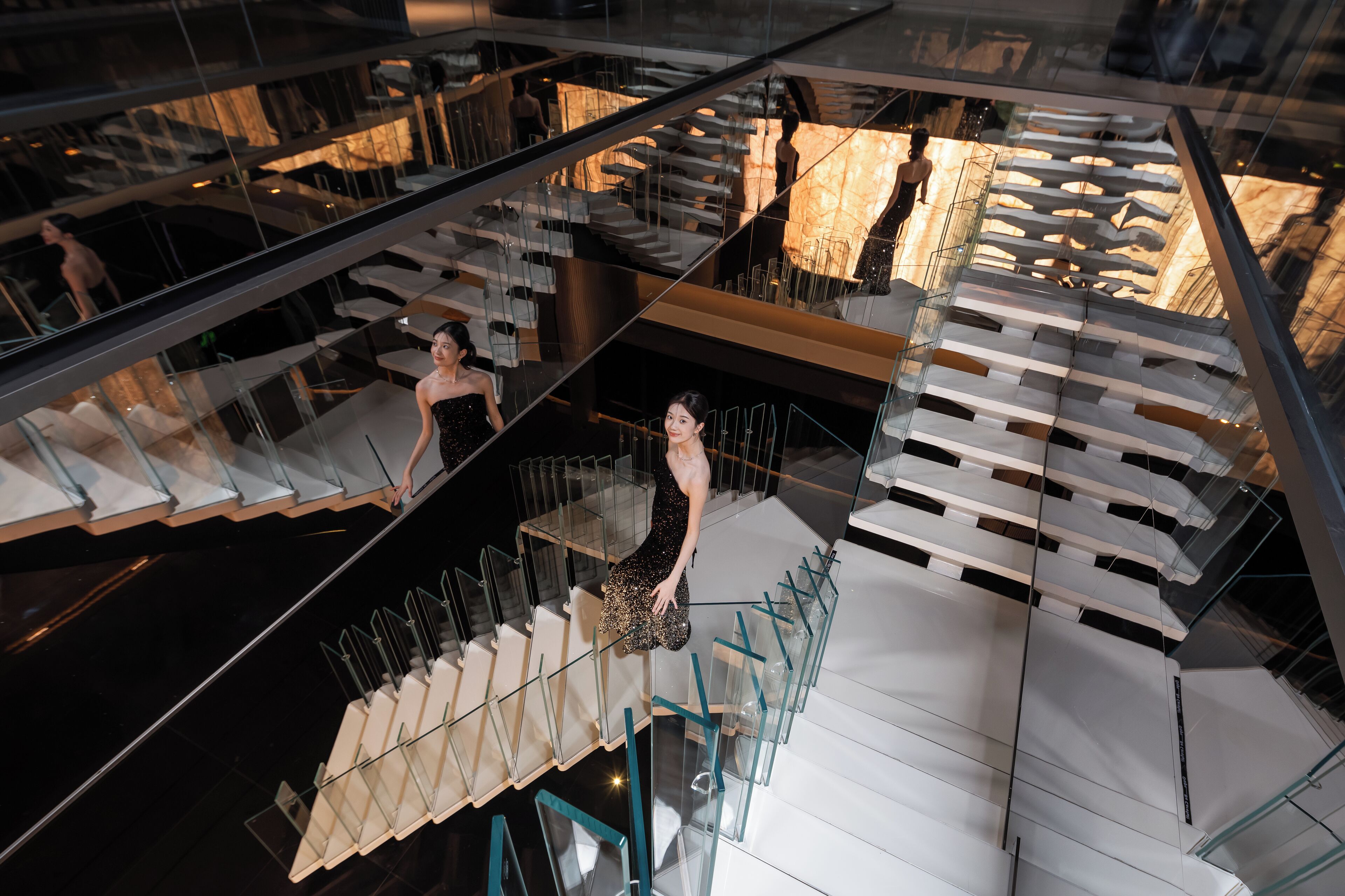 A modern interior with glass railings, a staircase, and a reflective floor.