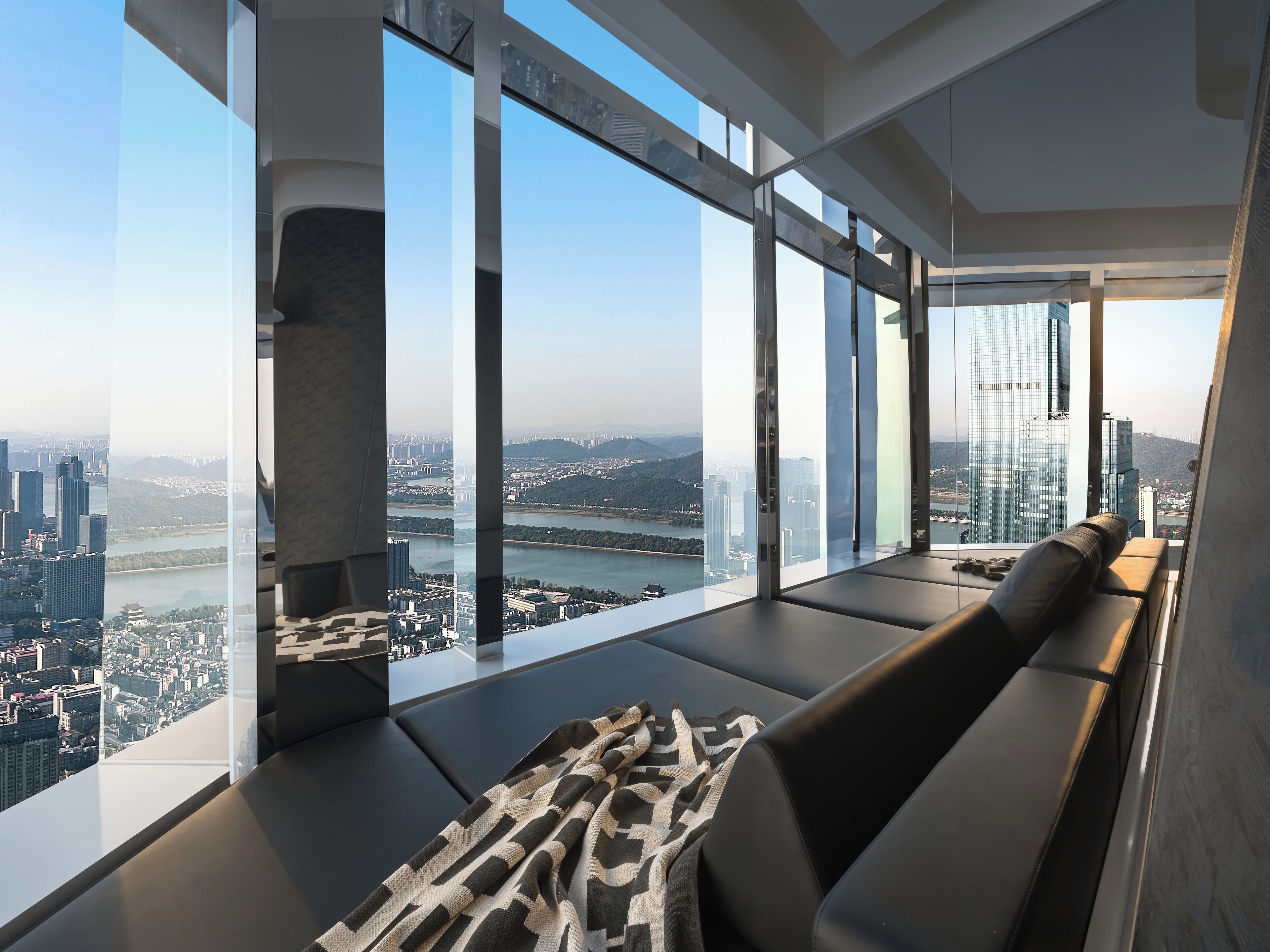 A modern interior with large windows, a sofa, and a view of a cityscape.