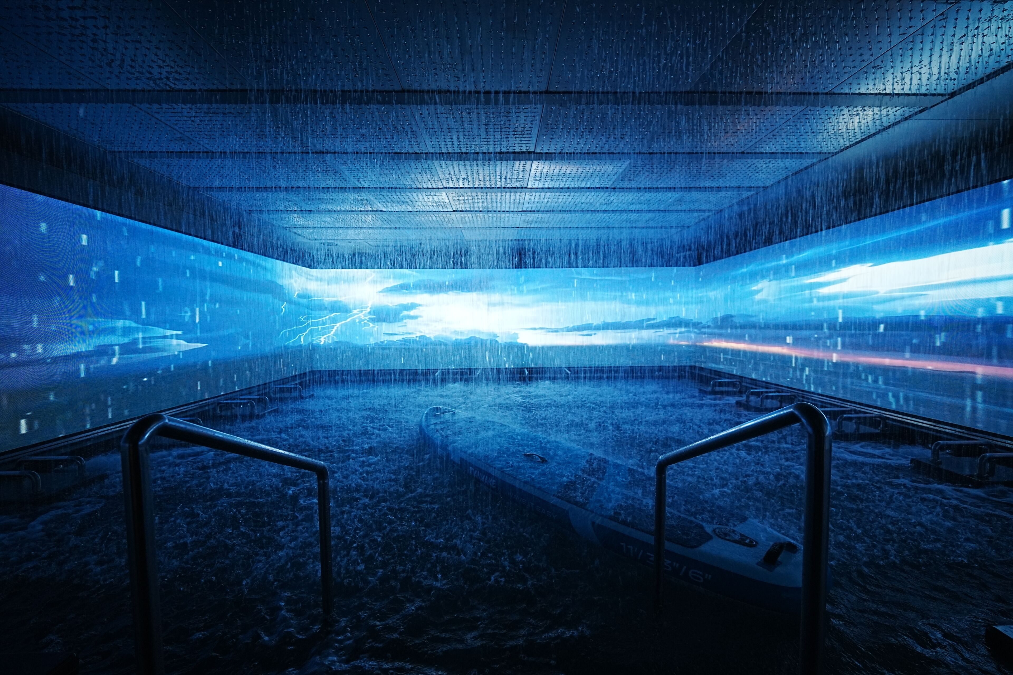 A spacious indoor area with a reflective floor, metal railings, and a central pathway.