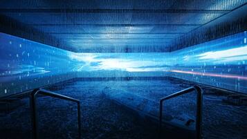 A spacious indoor area with a reflective floor, metal railings, and a central pathway.