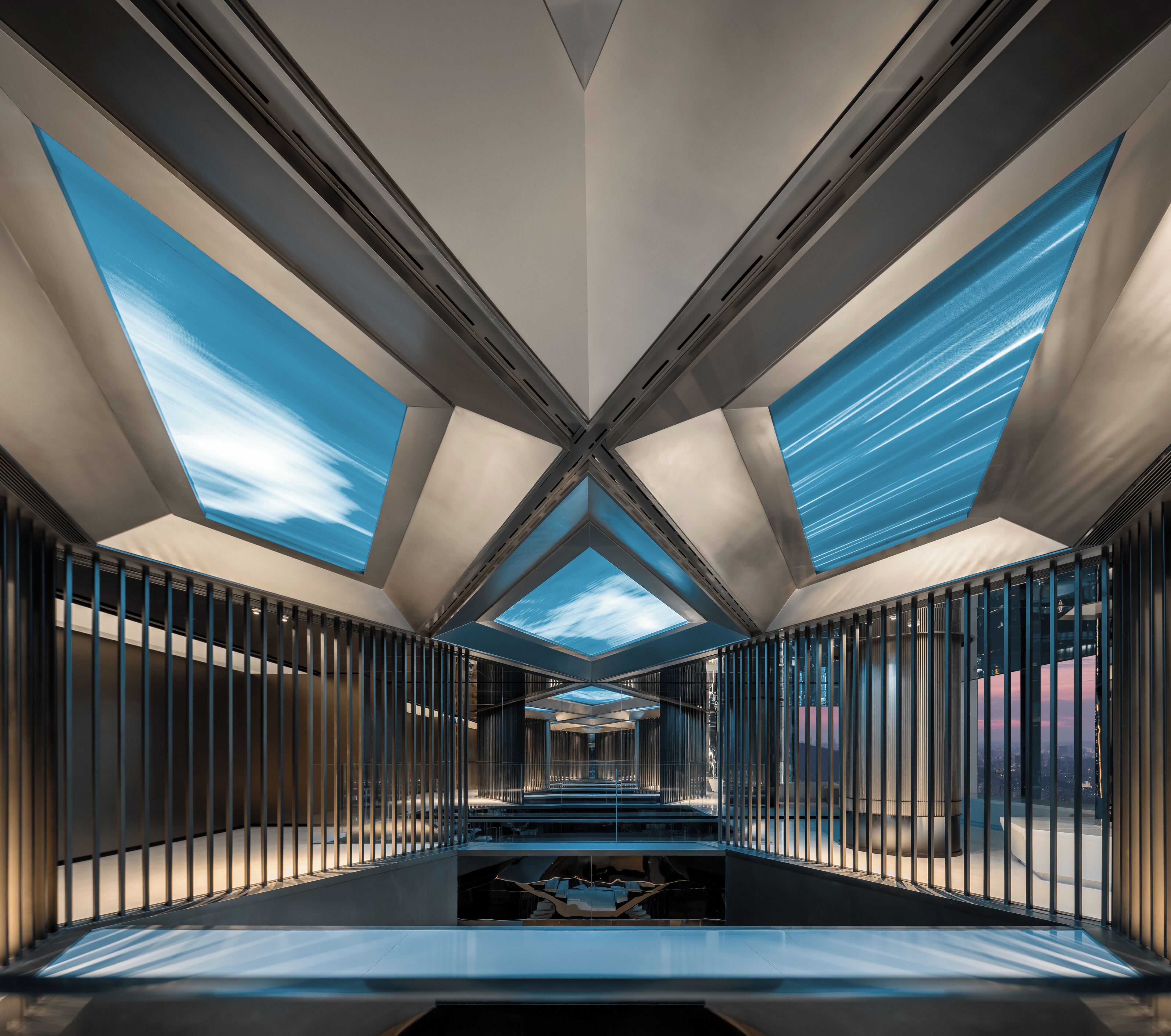 Un intérieur moderne avec un escalier central, des puits de lumière et une vue sur le paysage urbain.
