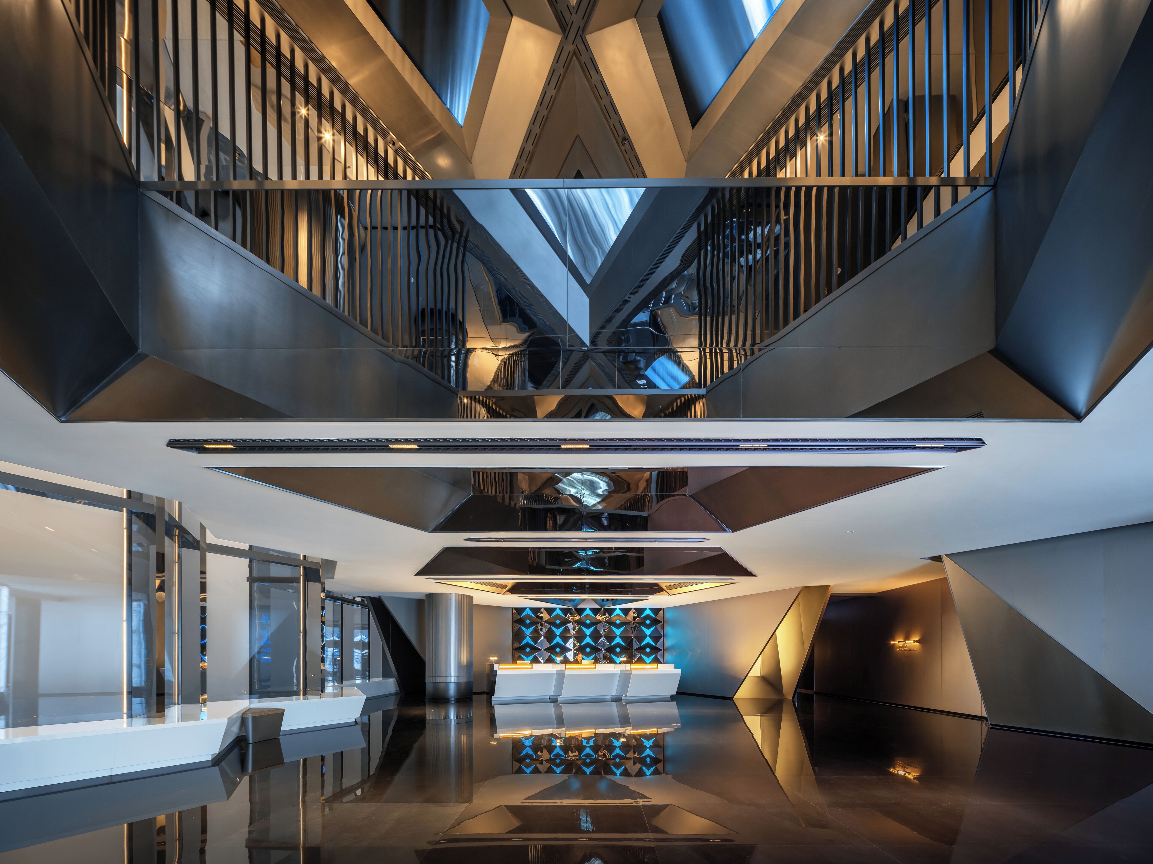 A modern interior with a central atrium, a reception desk, and a staircase.
