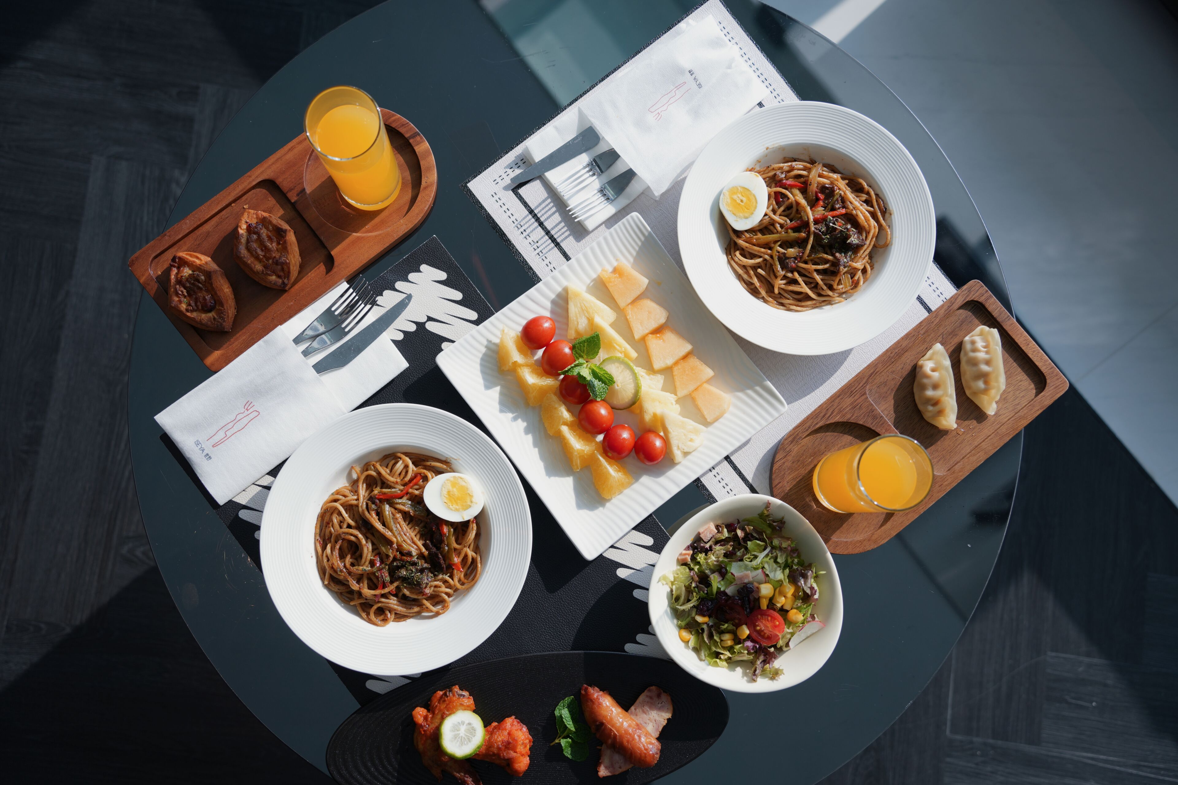 A table with various dishes including pasta, salad, and bread, arranged on a round table.