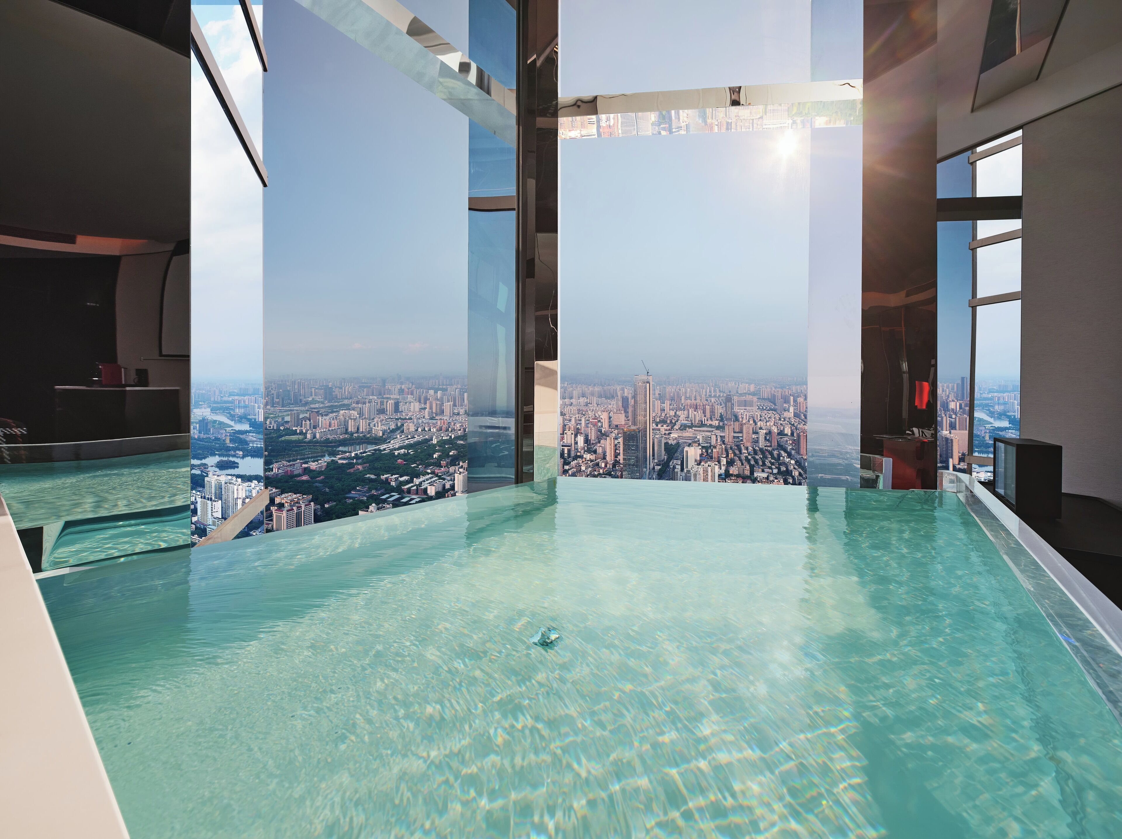 A high-rise building with a panoramic city view from an infinity pool.