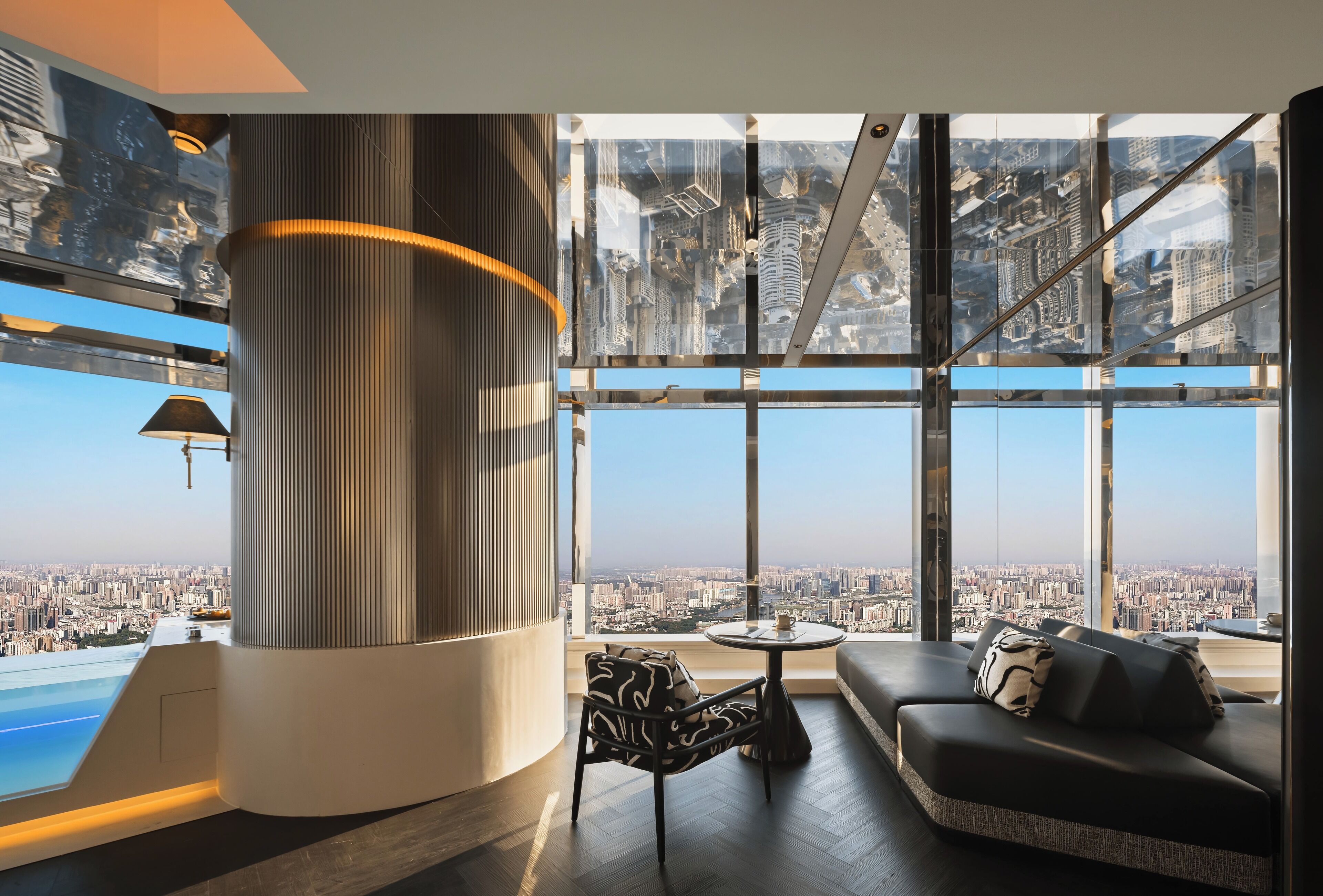 Un intérieur moderne avec une grande fenêtre, un canapé, un fauteuil et une petite table.
