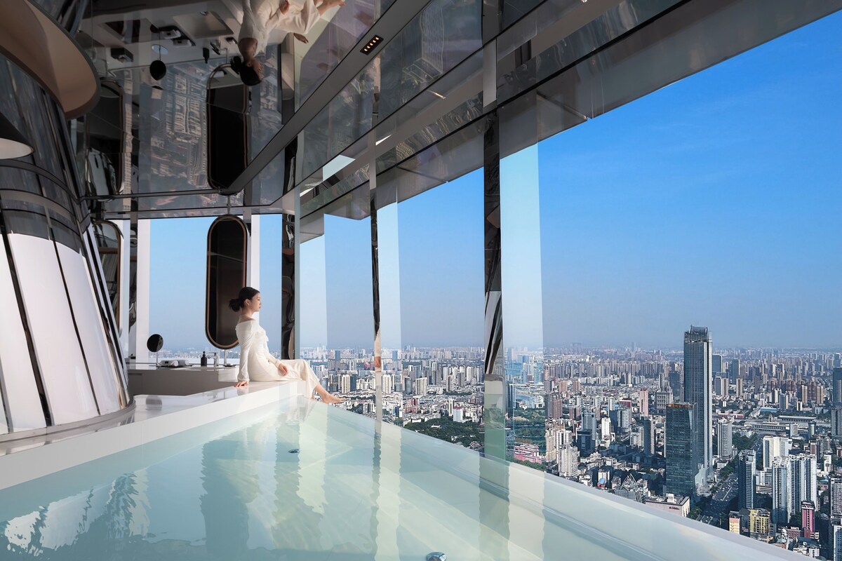 A high-rise building with a glass infinity pool and a city view.