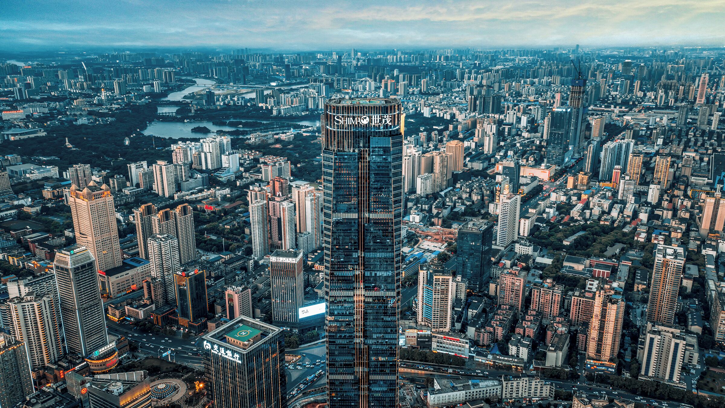 Un edificio de gran altura con fachada de vidrio moderna, rodeado de un entorno urbano denso con otros edificios altos.