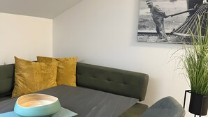 Zona pranzo moderna con tavolo scuro, panca imbottita verde e scultura a parete.
