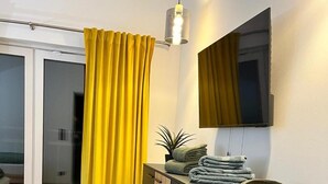 Un bagno moderno con una cabina doccia in vetro, una tenda gialla, un armadietto nero e uno specchio a parete.