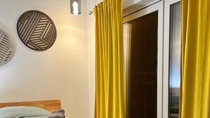 Un letto con struttura in legno, una coperta grigia e un asciugamano piegato.