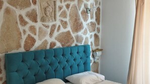 Ein Schlafzimmer mit einer Steinsturz, einem blauen, gepolsterten Kopfteil und einer weißen Bettdecke.
