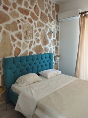 Ein Schlafzimmer mit einer Steinsturz, einem blauen, gepolsterten Kopfteil und einer weißen Bettdecke.
