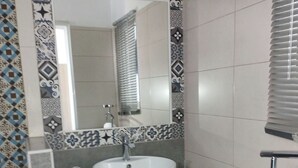 Ein Badezimmer mit einem weißen Waschbecken, einem Spiegel und einer Toilette.