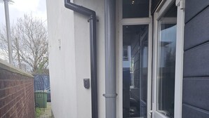 Un edificio residencial con fachada blanca, puerta de vidrio y portón de metal.
