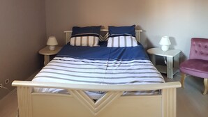 A bed with a white frame, two pillows, and a striped blanket. There are two bedside tables with lamps, a chair, and a wall with decorative plates. - T2 exceptional marina view (Arcachon)