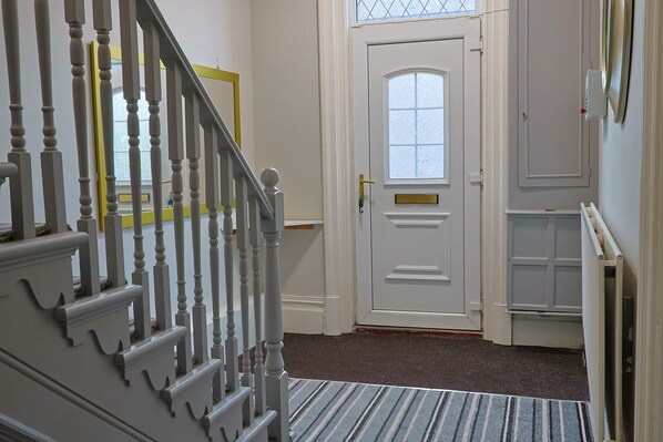 A staircase with a white handrail leading to a door with a window.