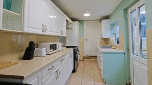 A kitchen with white cabinets, a microwave, a toaster, and a sink.