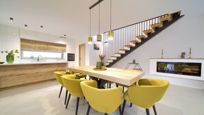 Een moderne keuken met een houten aanrecht, een inbouwoven en een eethoek met een houten tafel en gele stoelen.