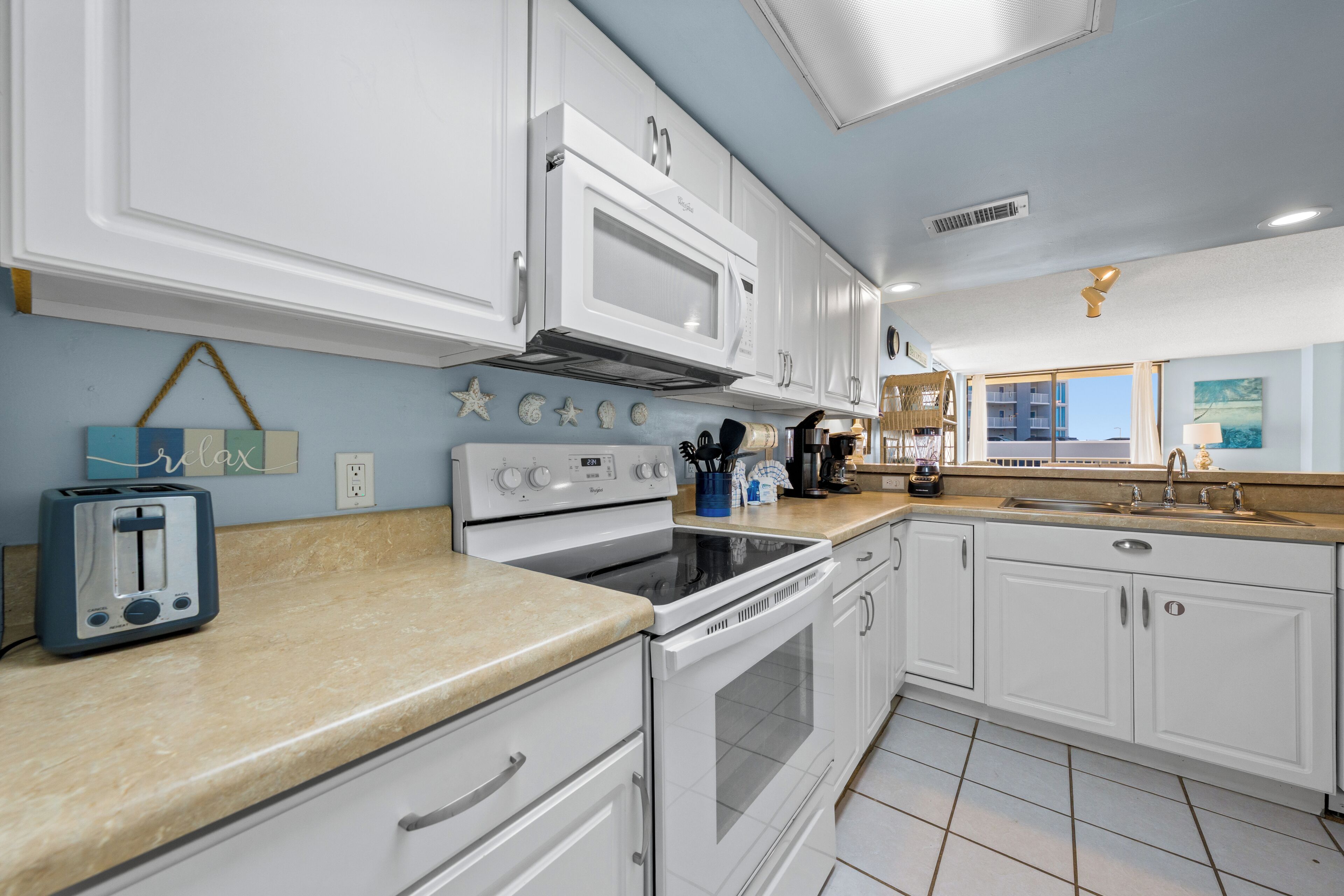 A kitchen with white cabinets, a microwave, a stove, and a toaster.