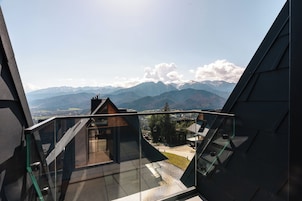 Un edificio moderno con un balcón de vidrio que da a un paisaje montañoso.