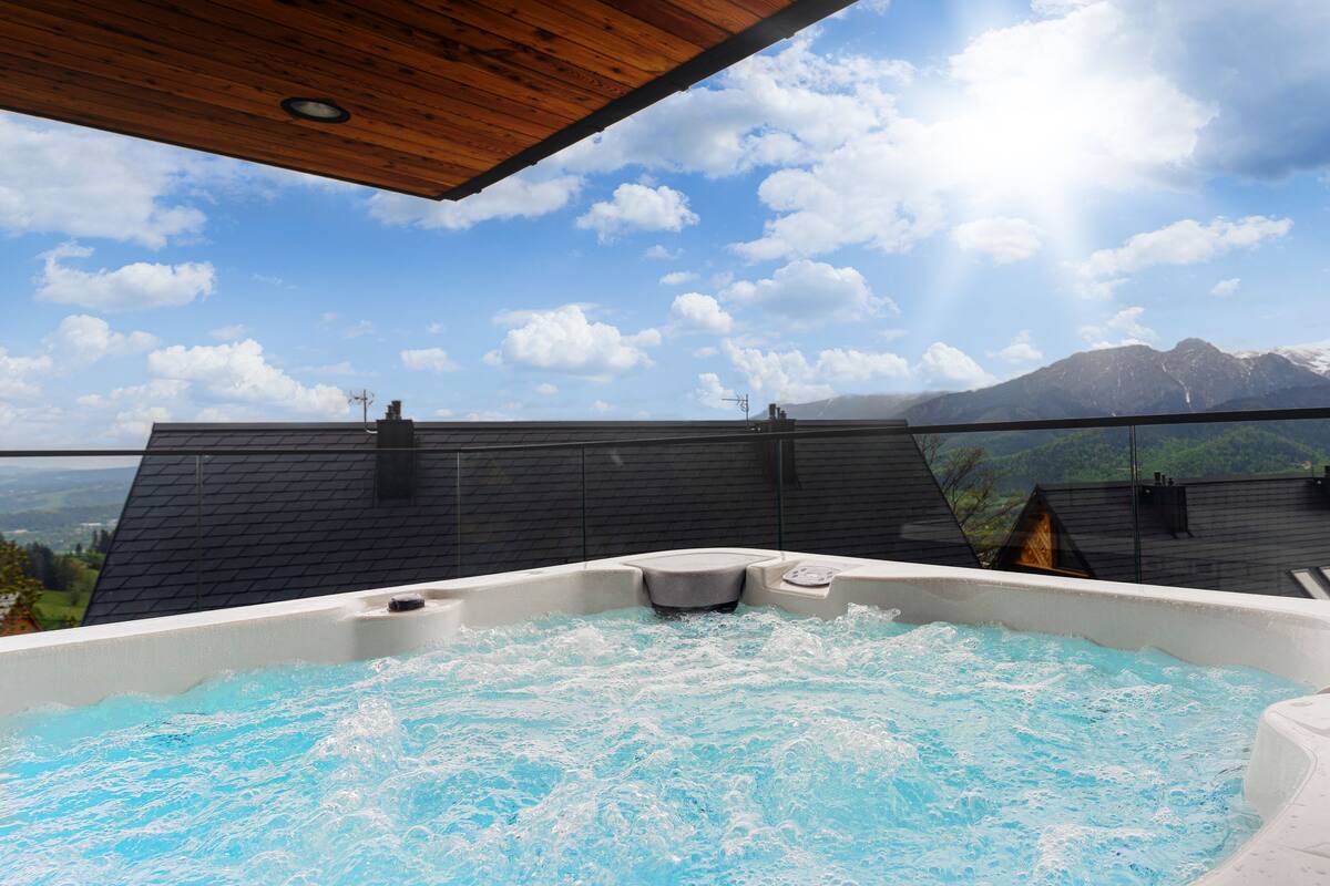 Un jacuzzi con vista a las montañas, techo de madera y techo negro.