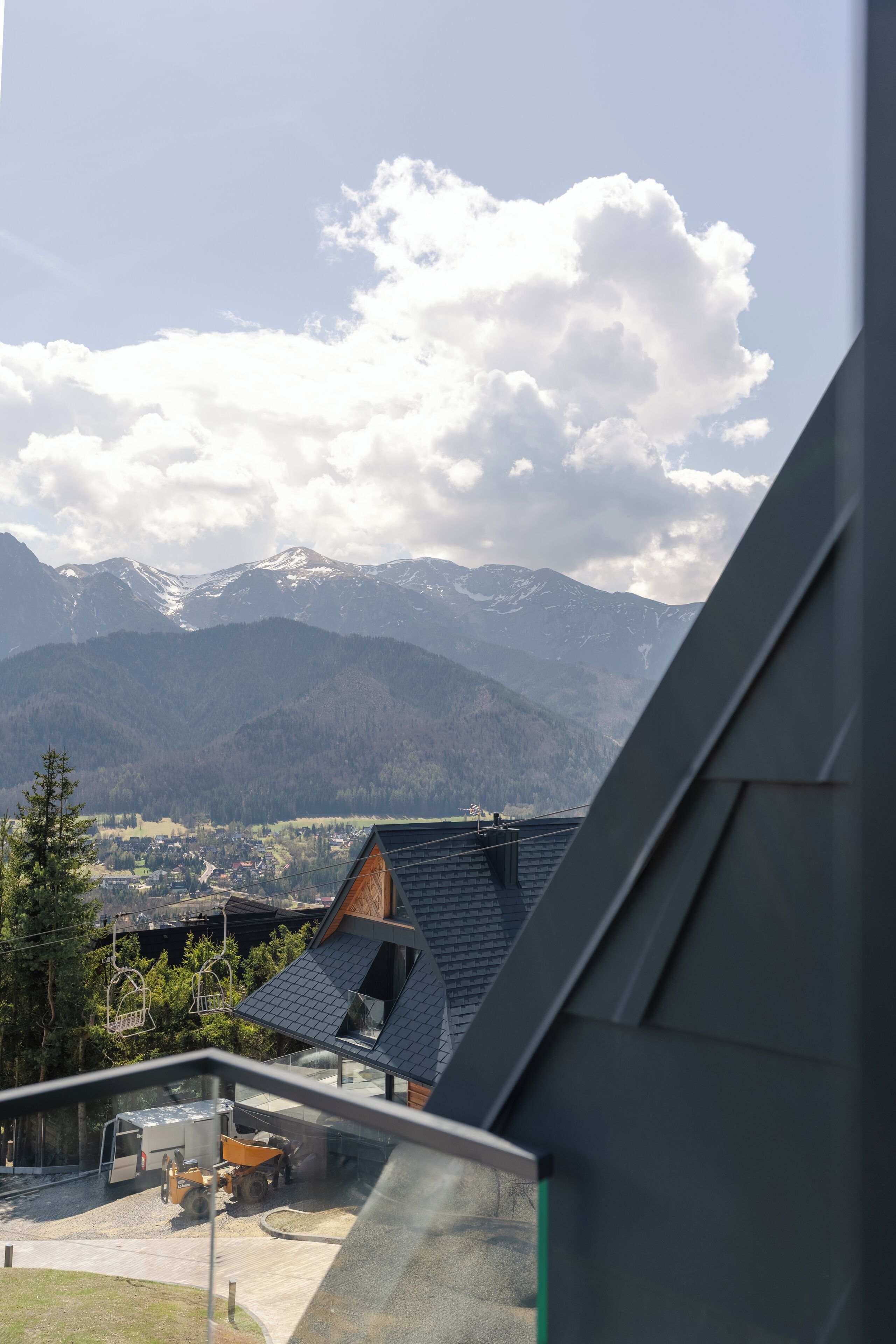 A mountain view from a building with a sloped roof, a parked truck, and a clear sky.