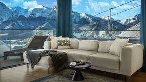 A modern living room with a large window overlooking snow-capped mountains, a beige sofa, a coffee table, and a wooden ceiling. - Salamandra Luxury Villas with Jacuzzi (Kościelisko)