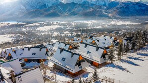 A snow-covered village with mountain views, chalet-style buildings, and a clear sky. - Salamandra Luxury Villas with Jacuzzi (Kościelisko)