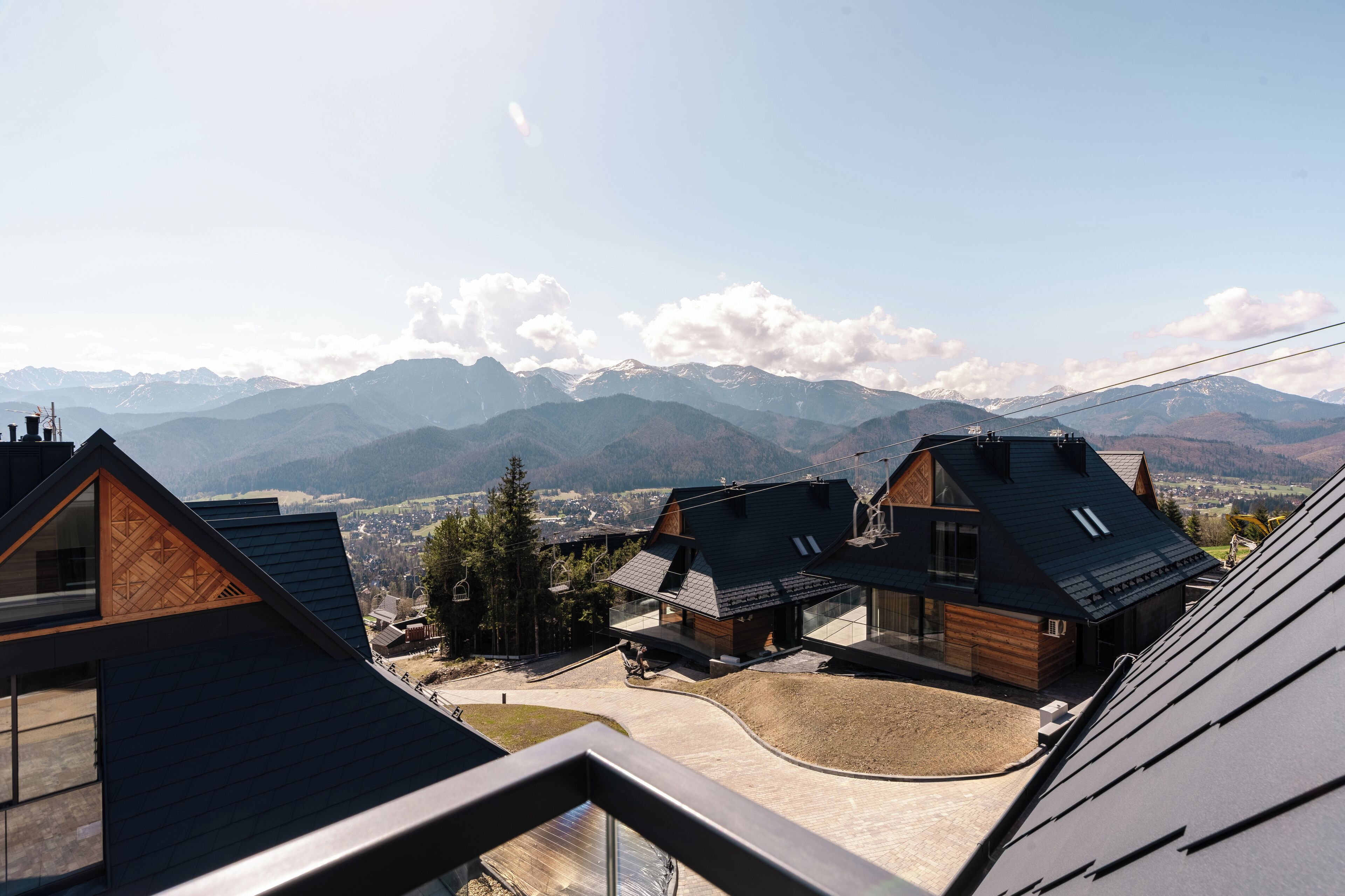 Una casa moderna con techo inclinado, ventanas amplias y vistas a montañas.