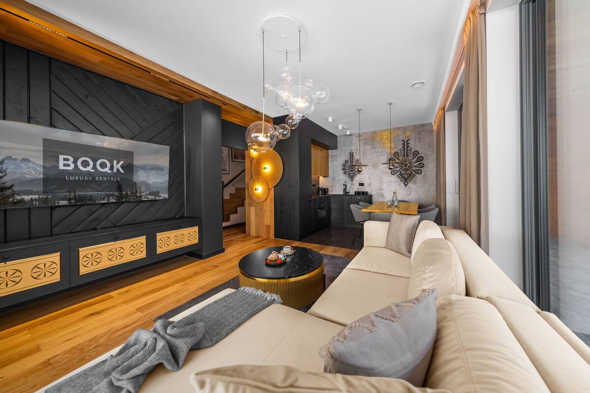 Una sala de estar moderna con un televisor grande, un sofá, una mesa de centro y una lámpara decorativa.