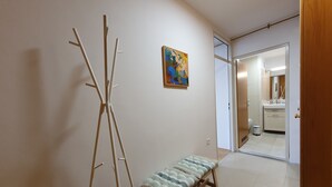 Un pasillo con un banco, un cuadro y una puerta que da a un baño.