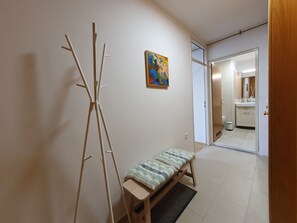 Ein Flur mit einer Bank, einem Bild und einer zur Toilette führenden Tür.