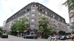 Un hotel de varios pisos con una fachada moderna, varios balcones y una entrada visible con un letrero azul.